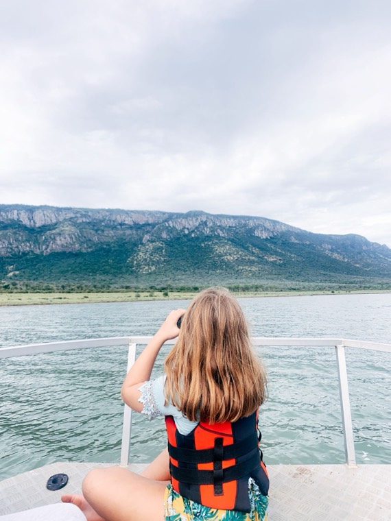 Guest in a life jacket looking at the Lubombo Mountains from a boat on Lake Jozini