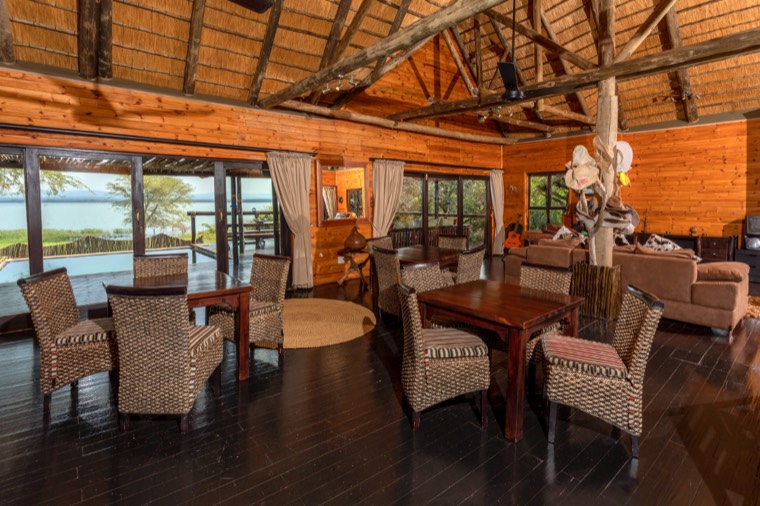 Timber-beamed main lodge with dining area and views over the lake